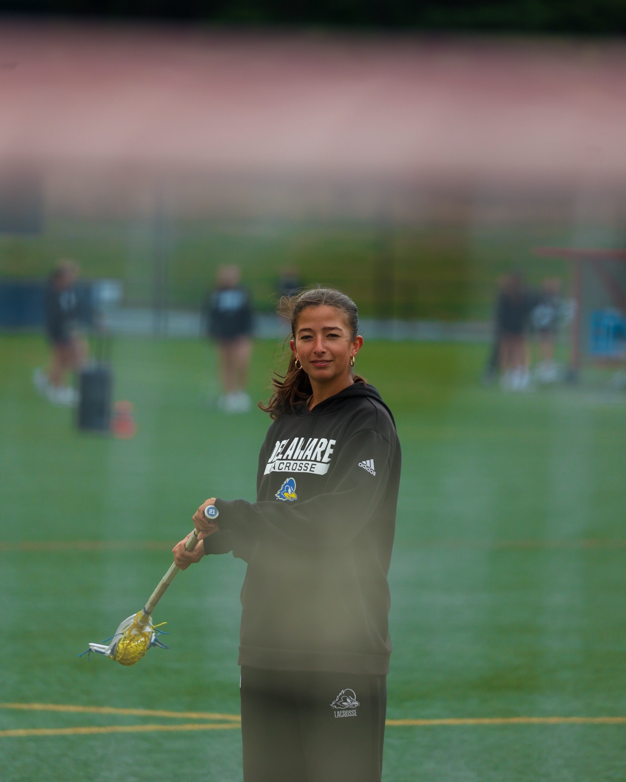 Delaware lacrosse player smiling with stick extended, double-exposure light effect