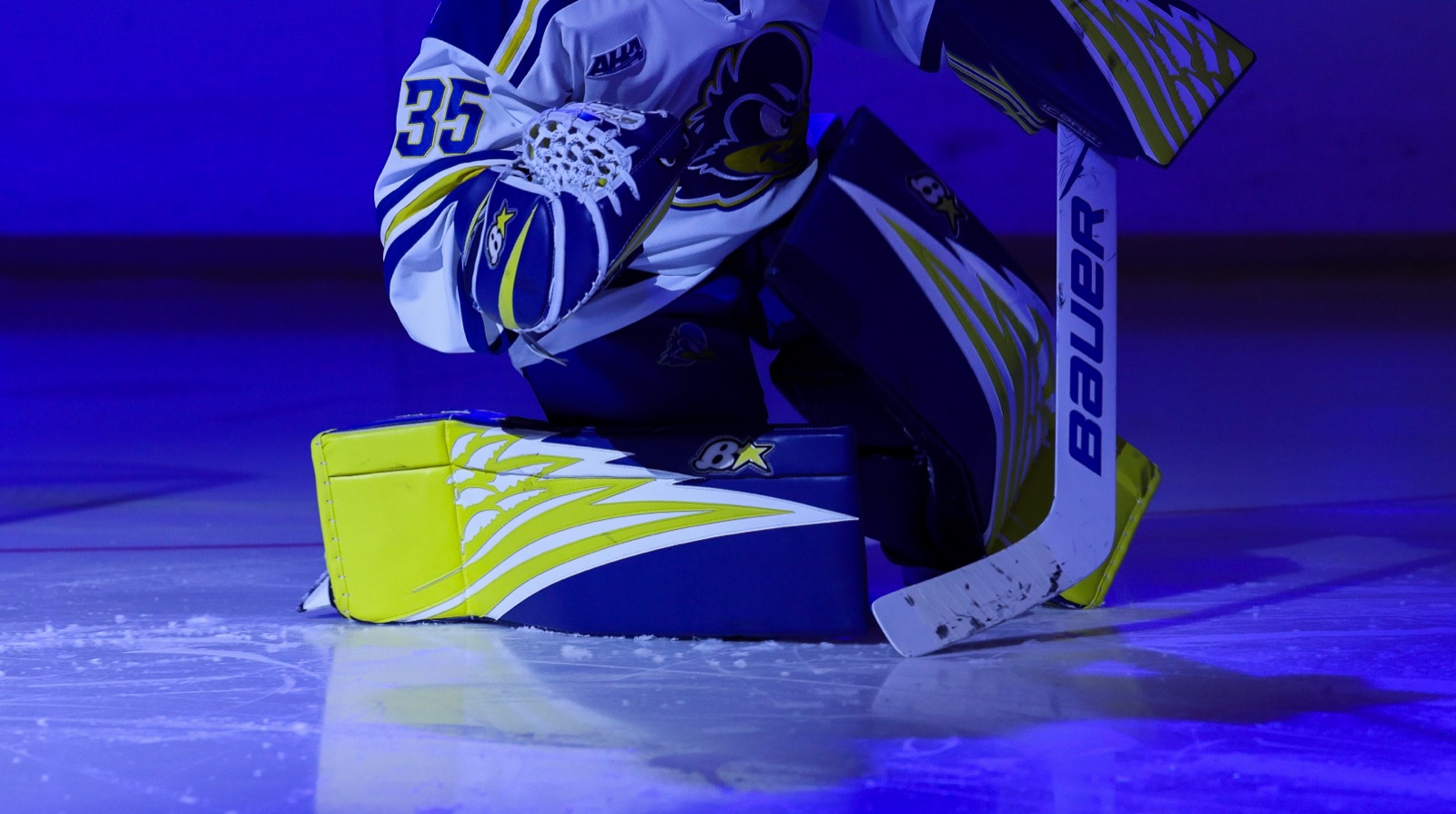 Delaware Women's Ice Hockey goalie leaning on the net in blue light